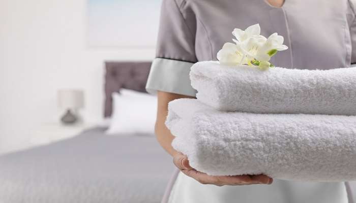 A lady carrying cleaned folded towels in a hotel room in Ashtamudi Resorts