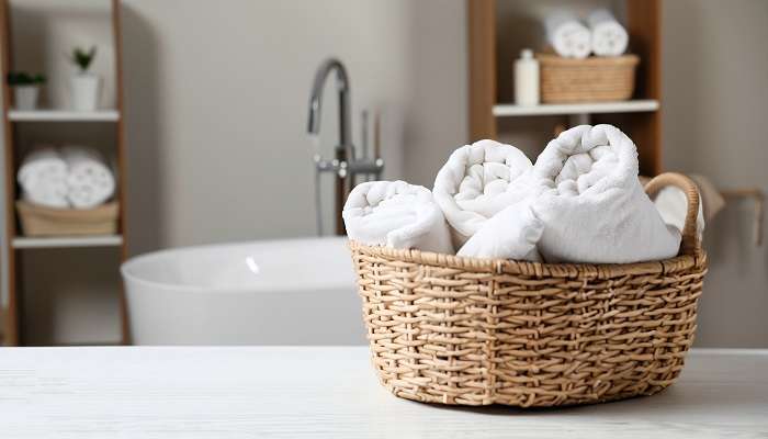 White cleaned rolled towels in a basket on the tabletop in the bathroom