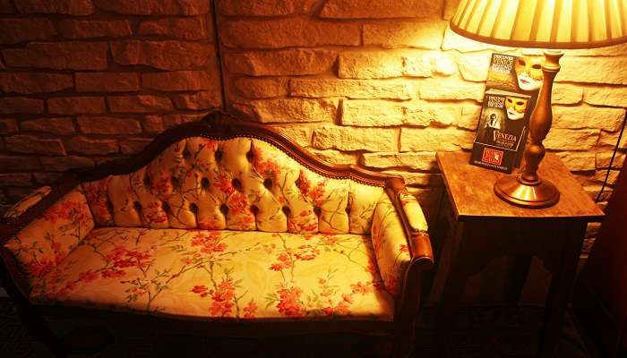 A cozy cottage room with a turned-on lamp kept at the bedside