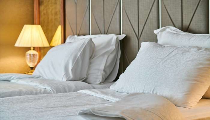 A white linen bed and pillows in a room in a hotel 