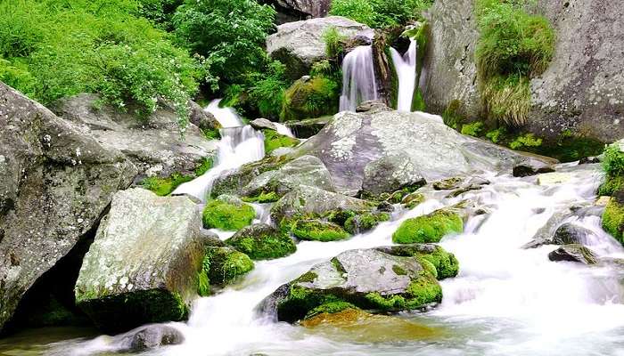Heavenly view of the Jogini Waterfall from the far with lush green beautiful surroundings during the skylight