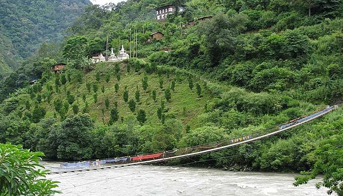Suspension bridge over the river with a distant view of a monastery