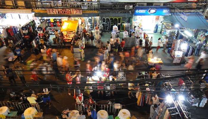 Khaosan Road in Bangkok at night with neon lights and crowded streets.