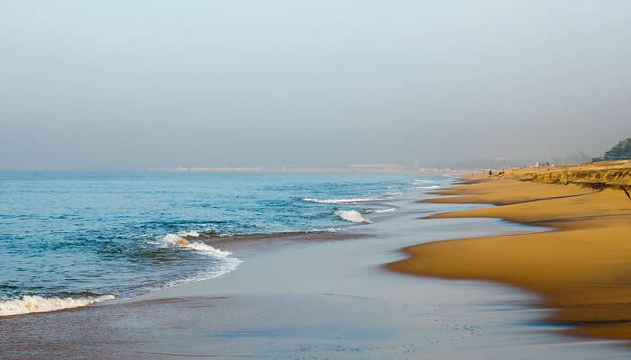 People standing by the sea of Kollam Beach under the sun