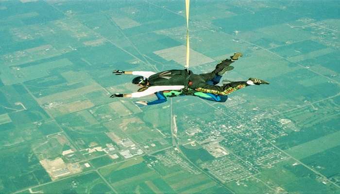 A skydiver free-falling over Wānaka with views of Lake Wānaka and surrounding mountains