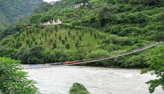 Suspension bridge over the river with a distant view of a monastery