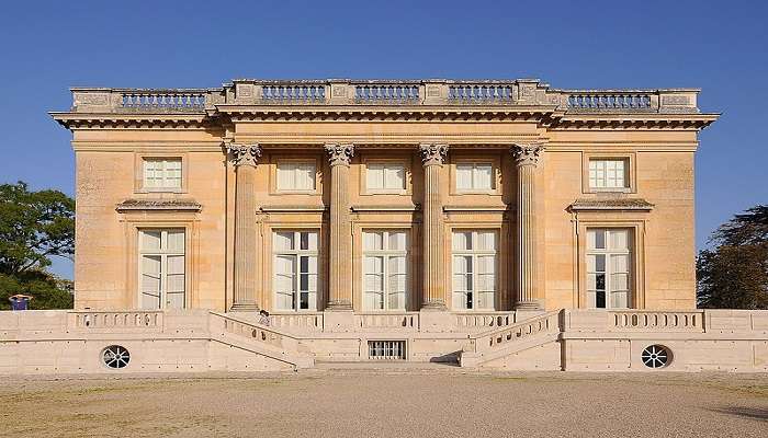 The Petit Trianon, surrounded by lush greenery near the palace of versailles.