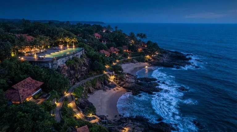 Aerial view of the private beach coves and cliff-edge pool at blue hour, Niraamaya Retreats Surya Samudra, Kerala, India
