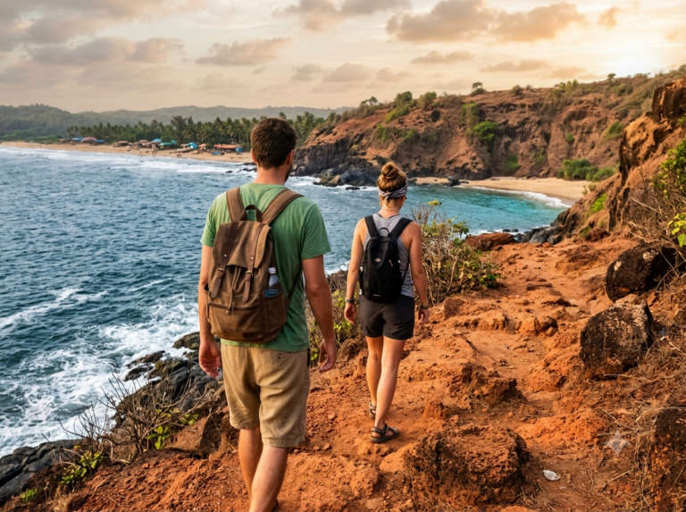 Two travellers walking the red-laterite cliff trail from Kudle Beach towards Half Moon Beach above, Gokarna, India