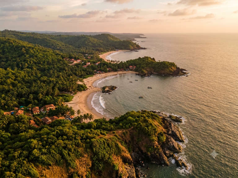 Kudle Beach at blue hour after sunset, a few beach-shack lights glowing under the palms and gentle waves, Gokarna, India