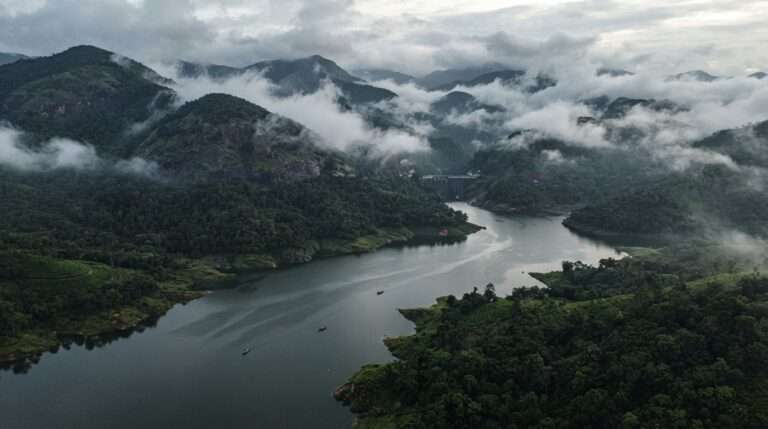 Reservoir and forested Western Ghats hills wrapped in rolling monsoon cloud, Idukki, Kerala, India