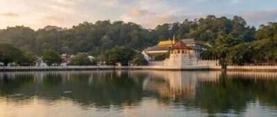 Sri Dalada Maligawa, the Temple of the Sacred Tooth Relic, viewed across Kandy Lake at golden hour.