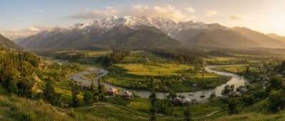 Kashmir valley panorama with green meadows, pine forests and snow-capped Pir Panjal peaks at golden hour