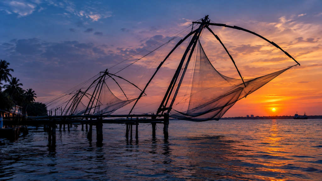 Alt: Chinese fishing nets of Fort Kochi silhouetted at dusk, a winter heritage stop in Kerala Note: confirmed: Chinese fishing nets named in Heritage section